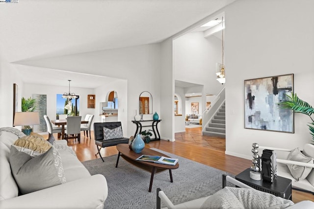 living room with wood-type flooring, high vaulted ceiling, and an inviting chandelier