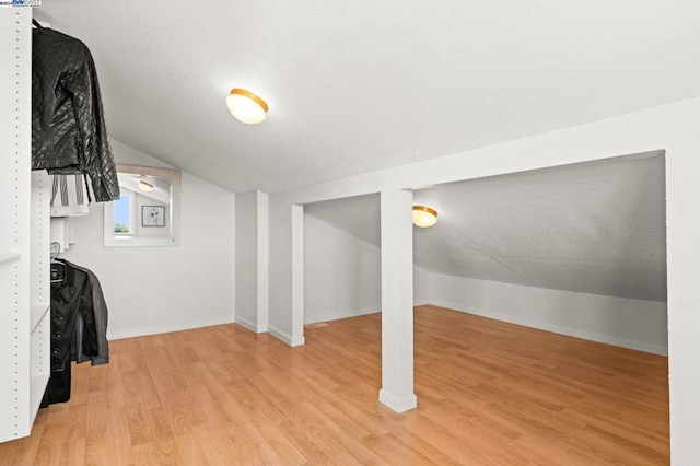 additional living space featuring light hardwood / wood-style floors and vaulted ceiling