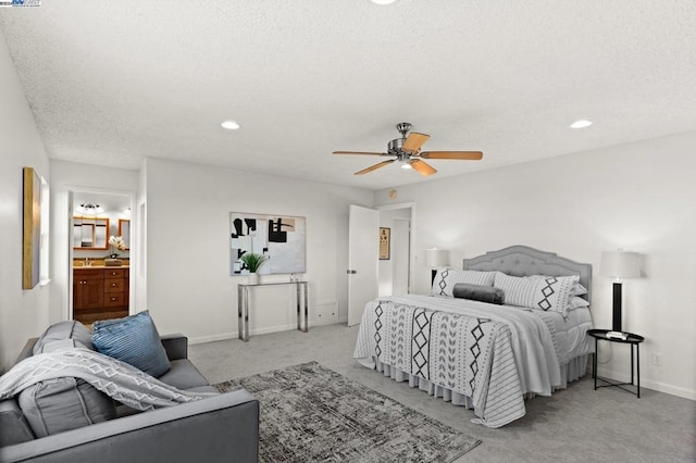 bedroom featuring ceiling fan, light colored carpet, a textured ceiling, and ensuite bath