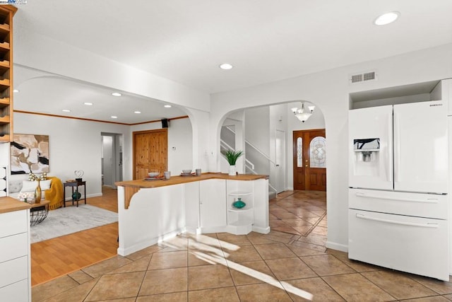 kitchen with kitchen peninsula, white cabinets, light hardwood / wood-style floors, and white refrigerator with ice dispenser