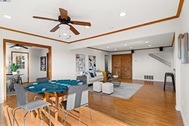 dining space with hardwood / wood-style flooring, ceiling fan, and crown molding