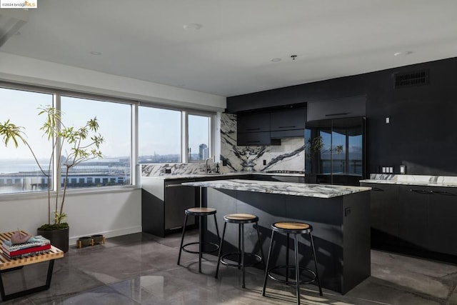 kitchen featuring black built in refrigerator, backsplash, a water view, a kitchen island, and a kitchen bar