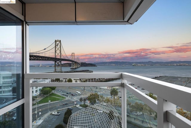 balcony at dusk featuring a water view