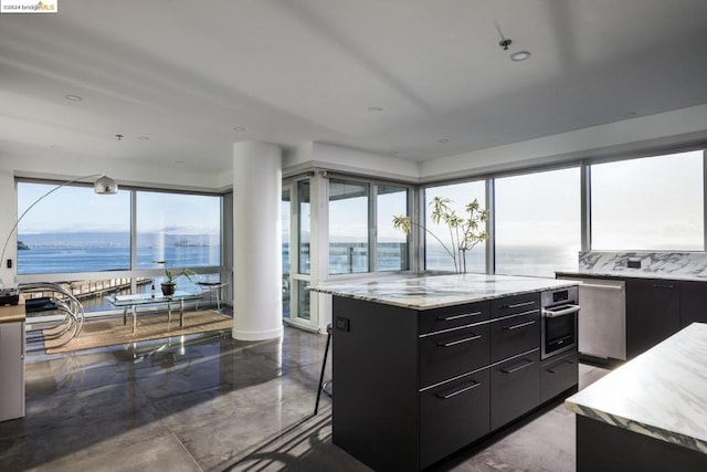 kitchen featuring a water view, decorative backsplash, a kitchen island, a breakfast bar area, and stainless steel appliances