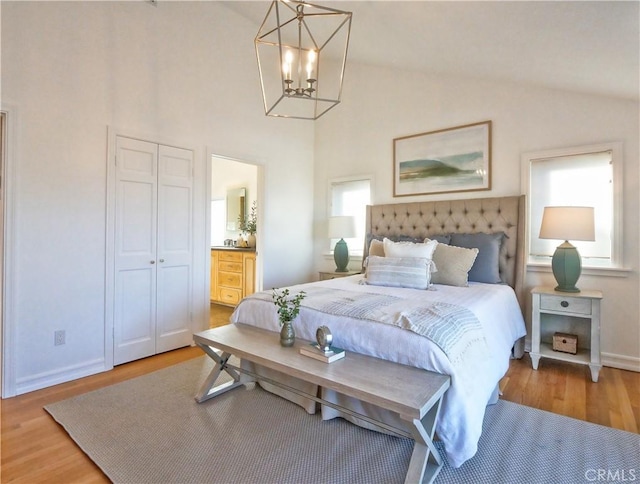 bedroom featuring hardwood / wood-style floors, an inviting chandelier, vaulted ceiling, and a closet