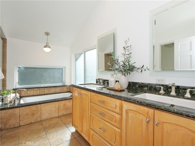 bathroom featuring tile patterned flooring, vanity, lofted ceiling, and tiled tub