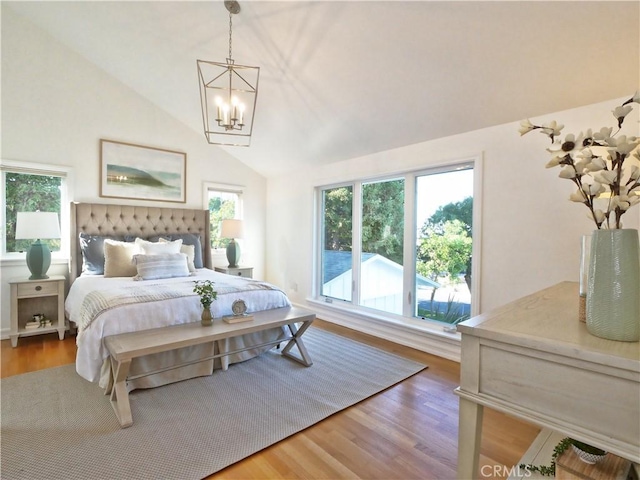 bedroom featuring a chandelier, hardwood / wood-style flooring, high vaulted ceiling, and multiple windows