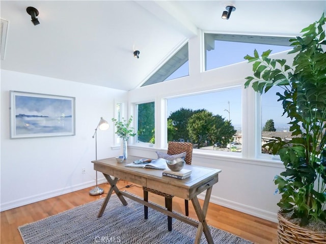 office area featuring lofted ceiling with beams, hardwood / wood-style flooring, and a healthy amount of sunlight