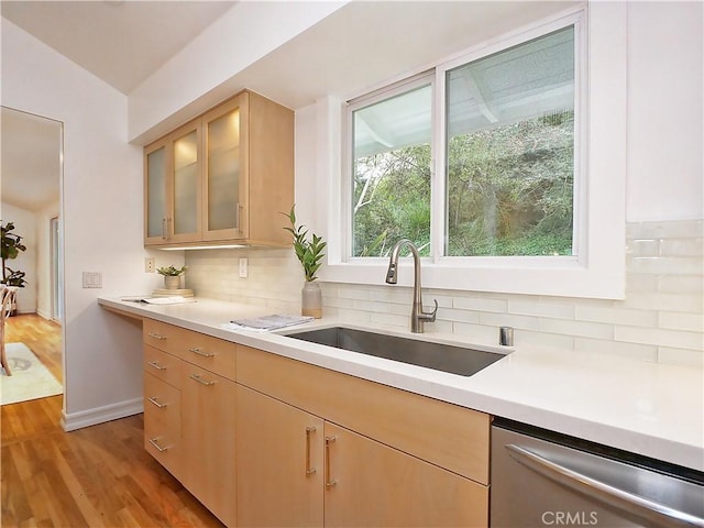 kitchen featuring sink, light hardwood / wood-style flooring, stainless steel dishwasher, backsplash, and light brown cabinetry