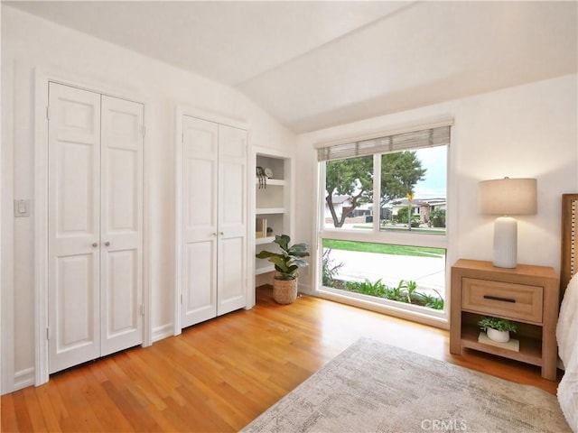 unfurnished room featuring hardwood / wood-style flooring, built in features, and lofted ceiling