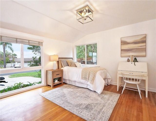 bedroom featuring wood-type flooring, multiple windows, and lofted ceiling