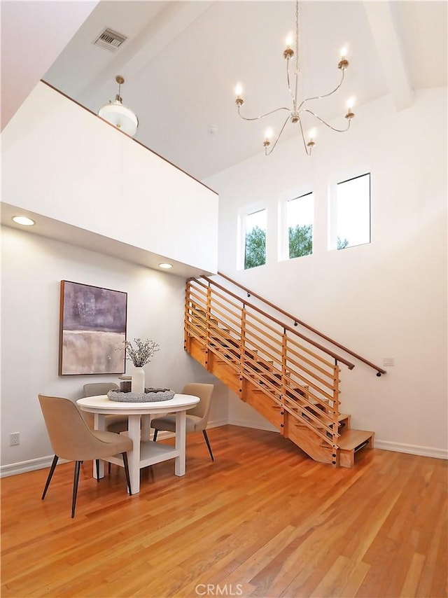 dining space with hardwood / wood-style floors, lofted ceiling with beams, and a notable chandelier