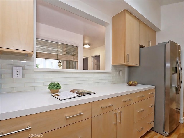 kitchen with backsplash, light wood-type flooring, stainless steel refrigerator with ice dispenser, and light brown cabinetry