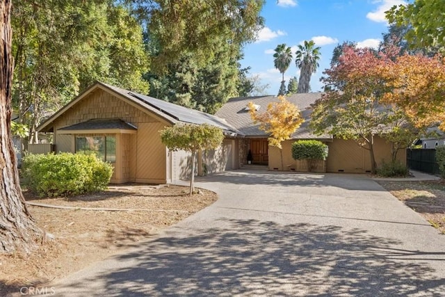 single story home featuring solar panels and a garage