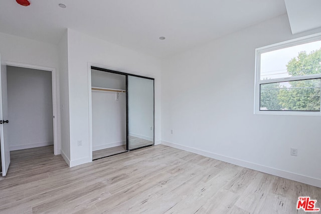 unfurnished bedroom featuring light hardwood / wood-style flooring and a closet