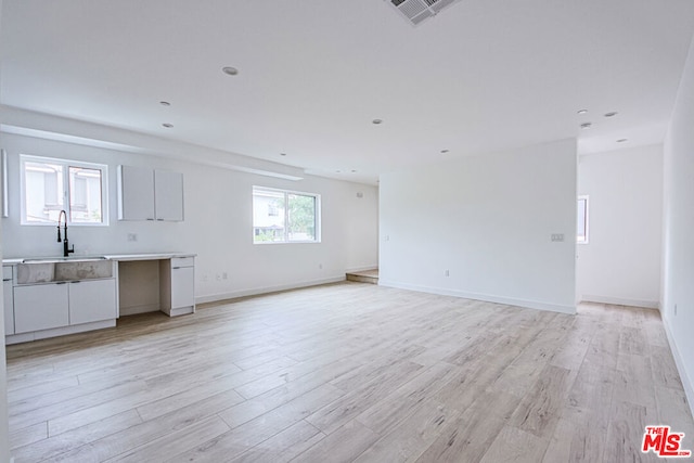 unfurnished living room featuring sink and light hardwood / wood-style flooring