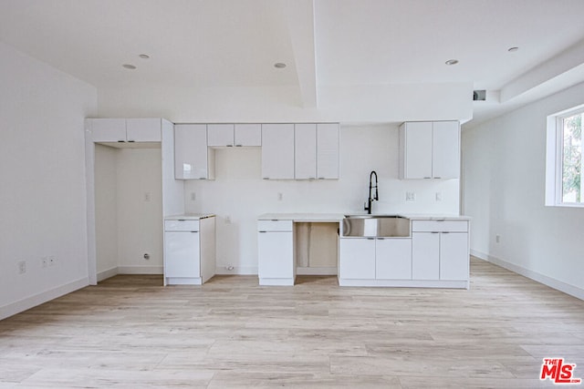 kitchen featuring white cabinets, beam ceiling, sink, and light hardwood / wood-style flooring