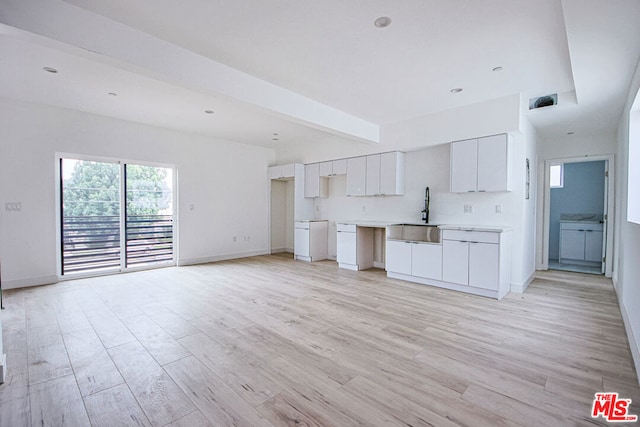 kitchen with white cabinets, beam ceiling, light wood-type flooring, and sink