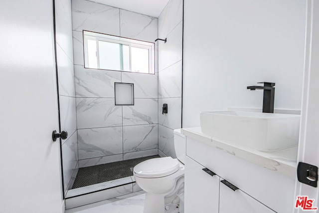 bathroom with vanity, toilet, and a tile shower