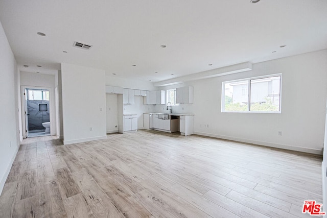 unfurnished living room with sink and light wood-type flooring