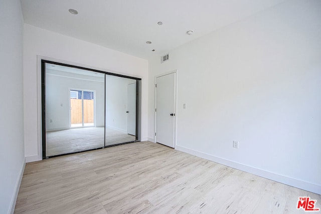 unfurnished bedroom with light wood-type flooring and a closet