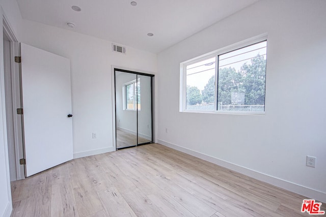 unfurnished bedroom featuring a closet and light hardwood / wood-style flooring