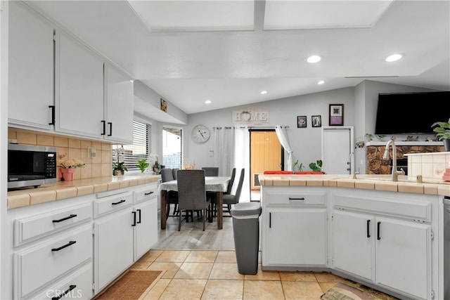 kitchen with tile countertops, white cabinets, lofted ceiling, and appliances with stainless steel finishes