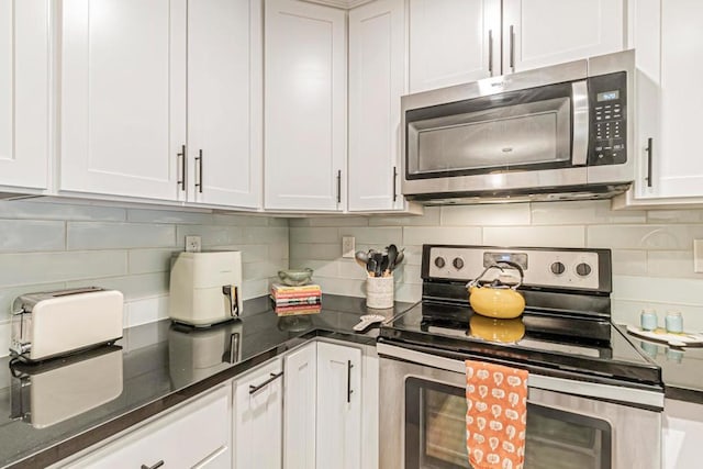 kitchen with decorative backsplash, appliances with stainless steel finishes, dark stone countertops, and white cabinetry