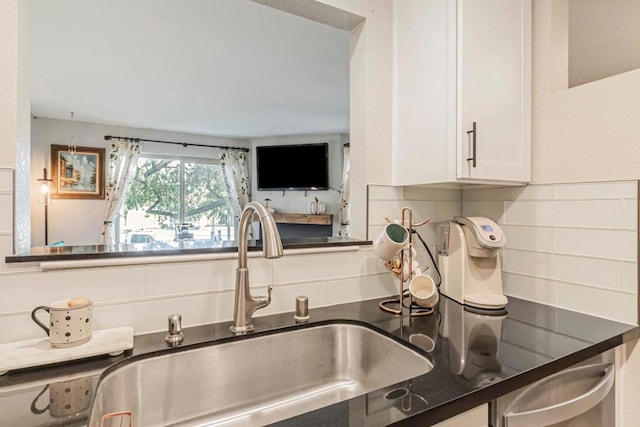 kitchen with decorative backsplash, sink, dark stone countertops, and white cabinetry