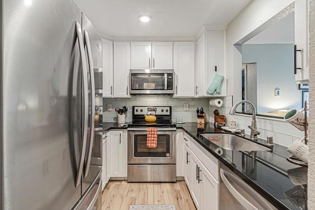 kitchen featuring light wood-type flooring, appliances with stainless steel finishes, white cabinetry, and sink