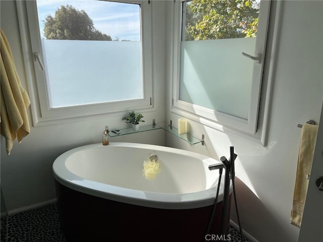 bathroom with tile patterned floors, a bathtub, and a healthy amount of sunlight