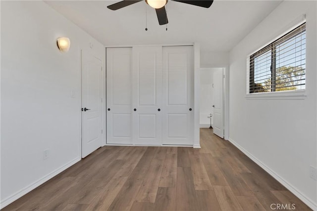 unfurnished bedroom with ceiling fan, a closet, and wood-type flooring