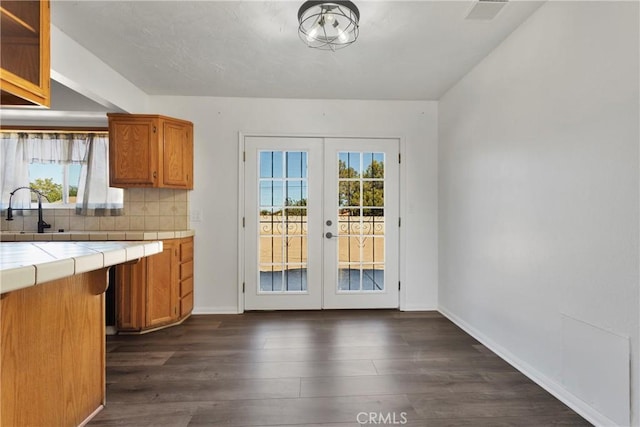 kitchen with tile countertops, plenty of natural light, dark hardwood / wood-style floors, and french doors