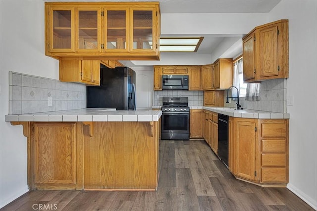 kitchen with black appliances, kitchen peninsula, and tile countertops