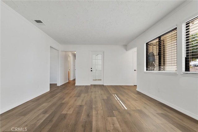 empty room with wood-type flooring and ornamental molding