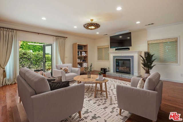 living room featuring a tile fireplace, hardwood / wood-style floors, and ornamental molding