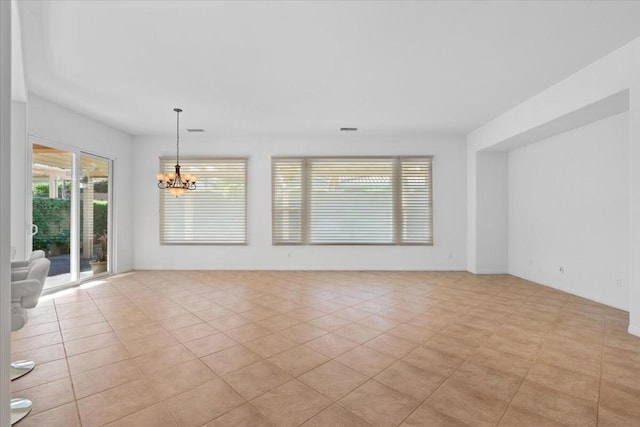 tiled spare room with an inviting chandelier