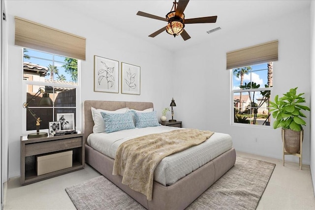 bedroom featuring multiple windows, light colored carpet, and ceiling fan