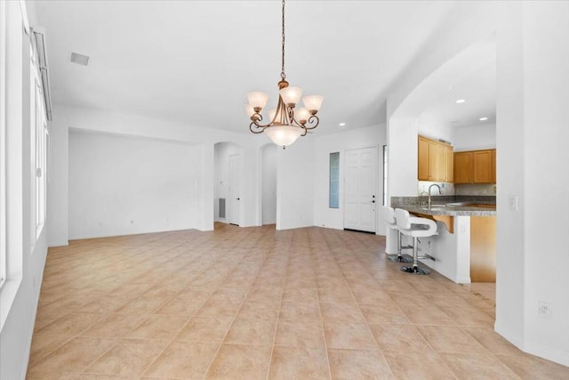 unfurnished living room featuring a chandelier, light tile patterned floors, and sink