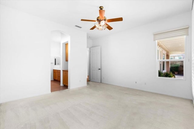 unfurnished bedroom with ensuite bathroom, ceiling fan, and light colored carpet