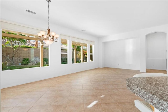 tiled empty room featuring a notable chandelier