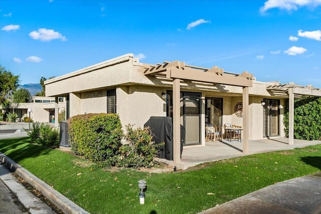 back of property with a pergola, a patio, and a lawn