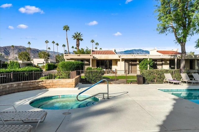 view of swimming pool with a mountain view, a community hot tub, and a patio area