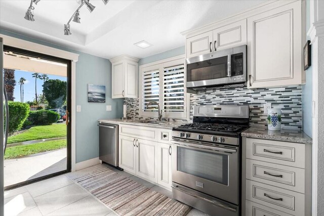 kitchen featuring decorative backsplash, white cabinets, stainless steel appliances, and light tile patterned floors