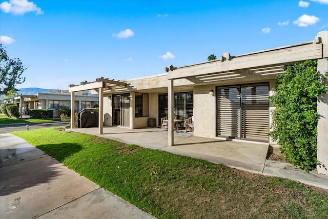 rear view of house featuring a yard, a pergola, and a patio area