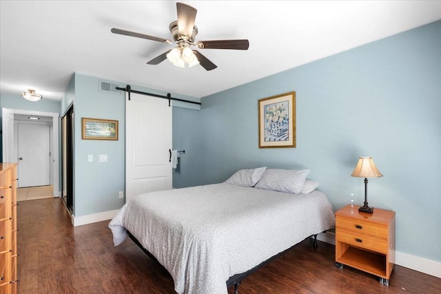 bedroom with a closet, a barn door, dark hardwood / wood-style floors, and ceiling fan