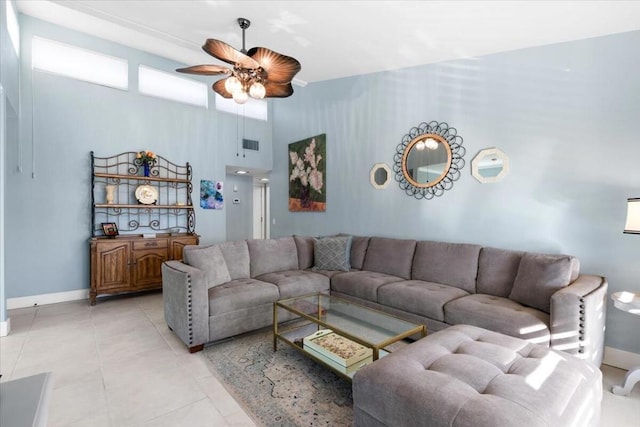 living room featuring ceiling fan, light tile patterned floors, and a high ceiling