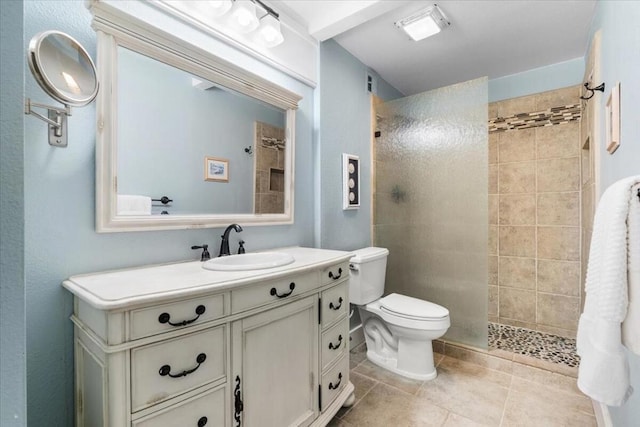 bathroom with tiled shower, vanity, tile patterned floors, and toilet