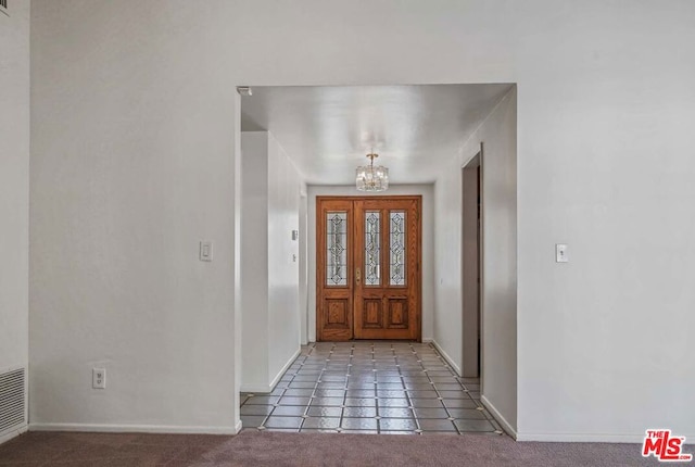 carpeted entryway featuring a chandelier