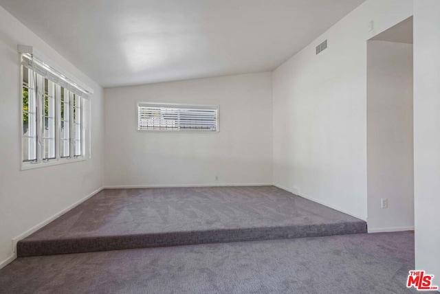 carpeted empty room with plenty of natural light and vaulted ceiling